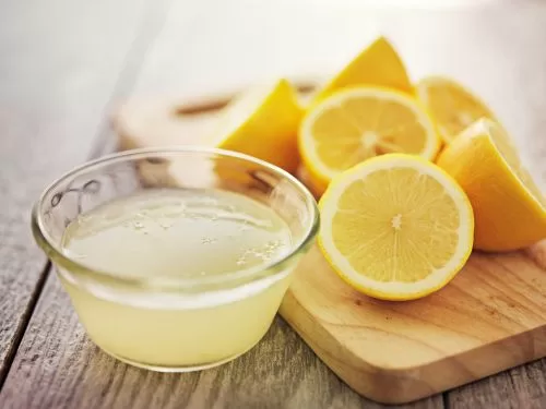 Limoni tagliati su tagliere con bicchiere del loro succo di fianco